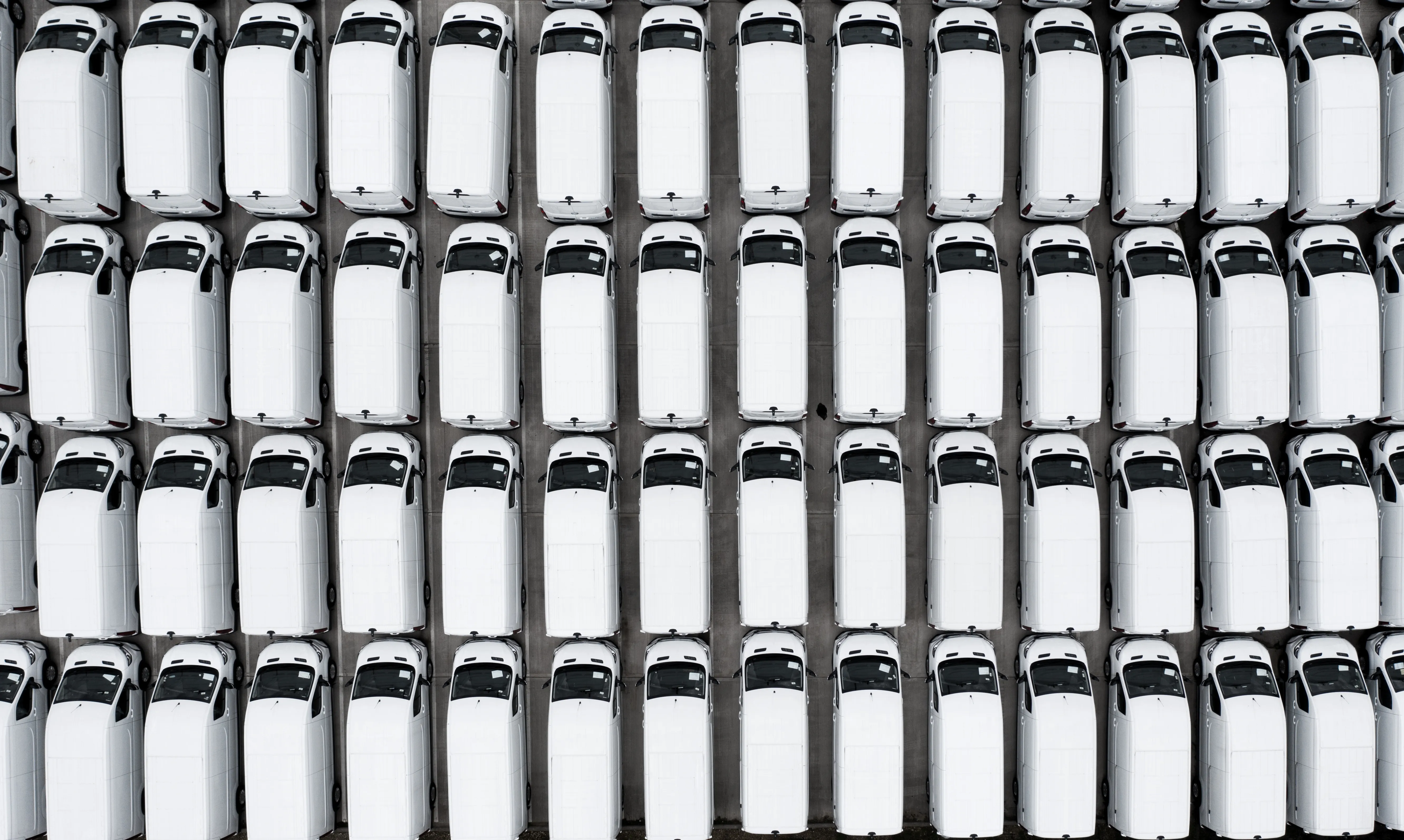 Full frame aerial view of new white vans parked together after manufacturing for import and export
