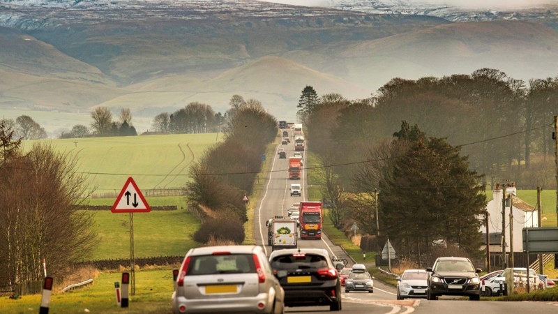 A66 in the north of England, showing vehicles, scenery either side of the road and a traffic sign