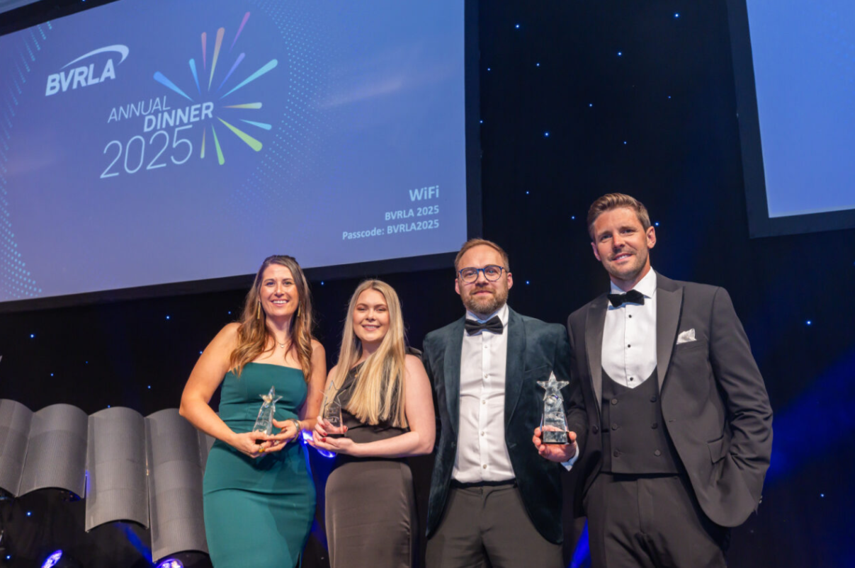 Two female and two male award winners posing with their trophies on stage as part of the black-tie Annual Dinner event