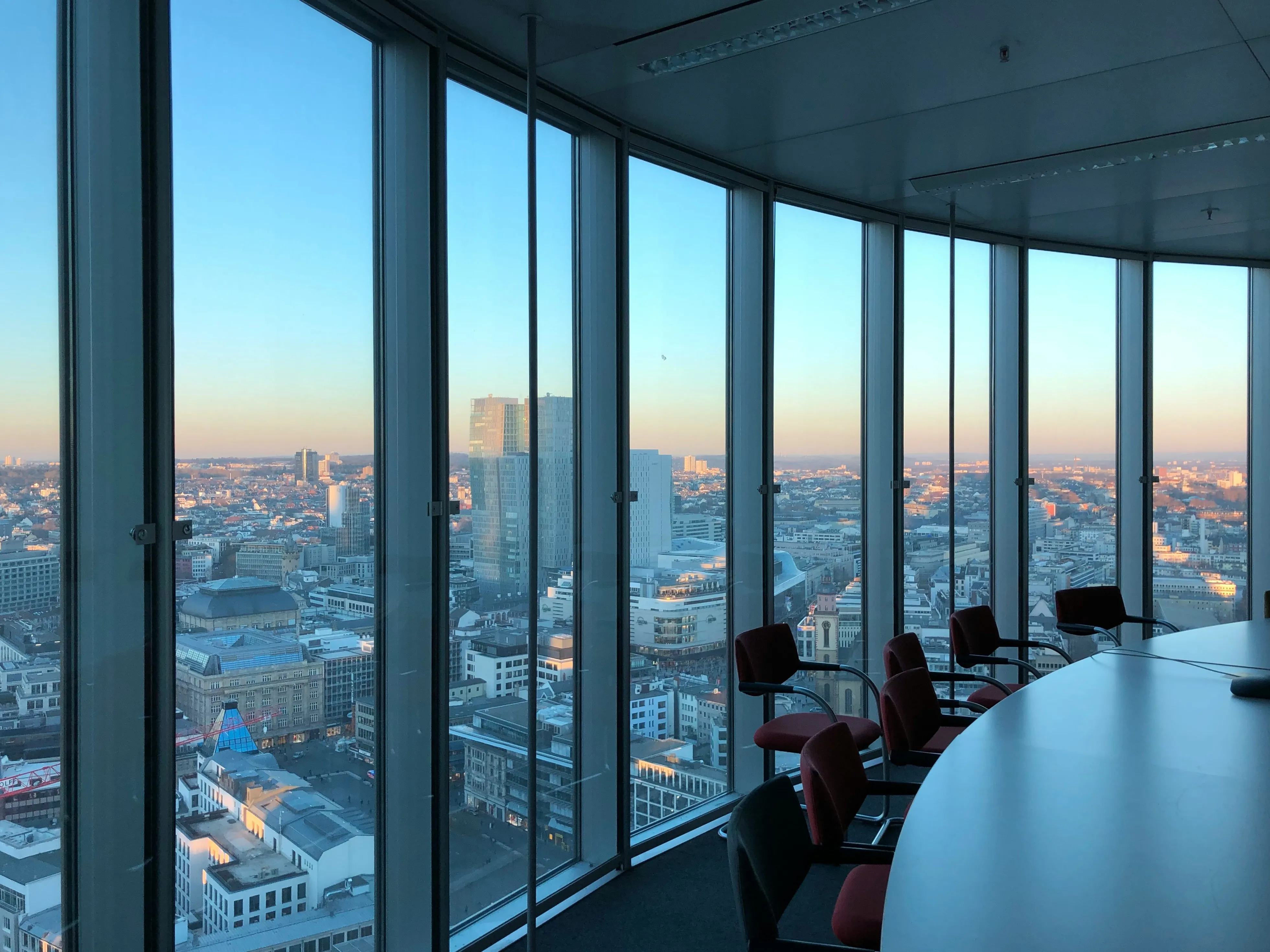 A meeting room with red chairs around a table 