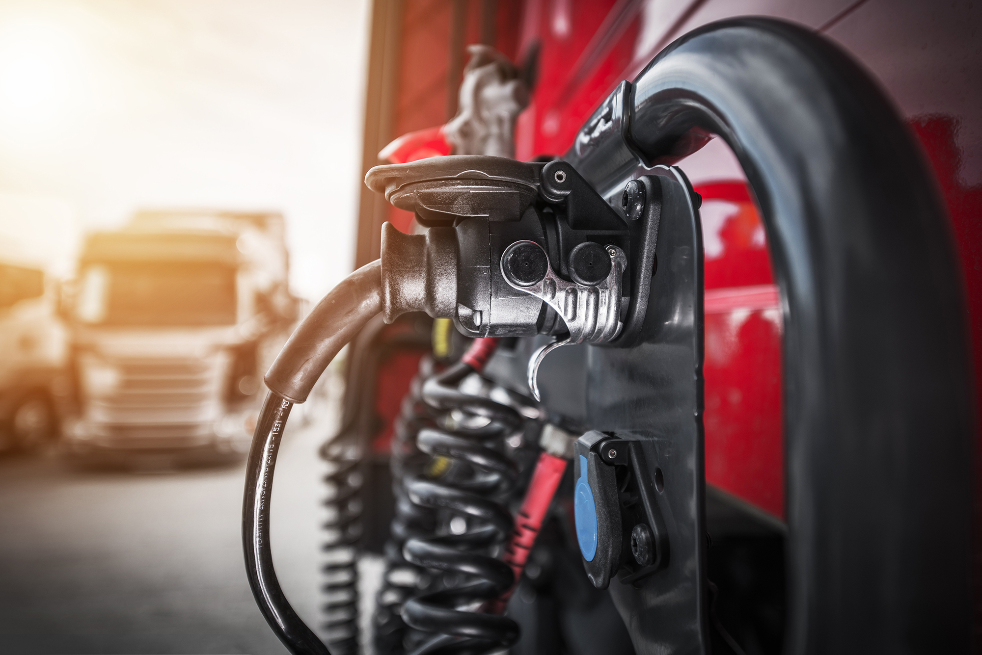 An electric HGV heavy goods vehicle at a charging point, another HGV in background