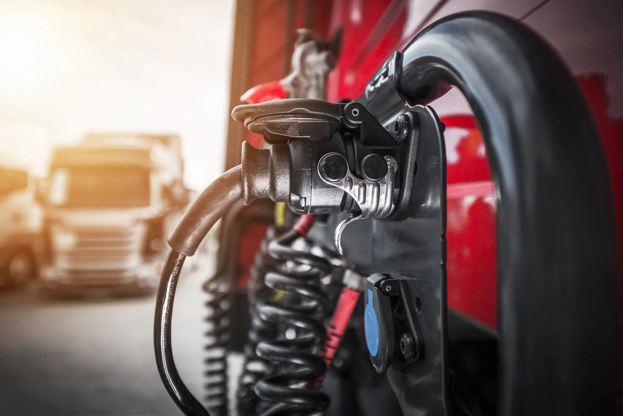 An electric HGV heavy goods vehicle at a charging point, another HGV in background