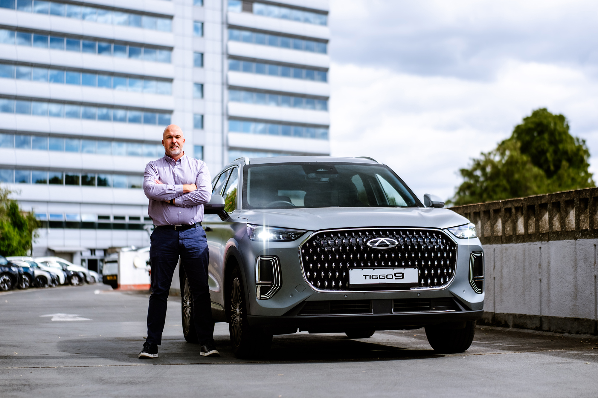 Stephen Powell, Head of Fleet at Chery UK standing next to a Chery automobile in an urban setting