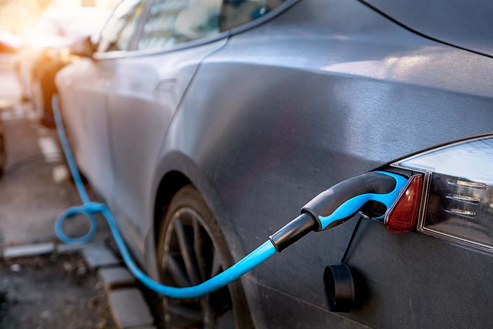Dark grey car on charge with a blue charger in forefront of image