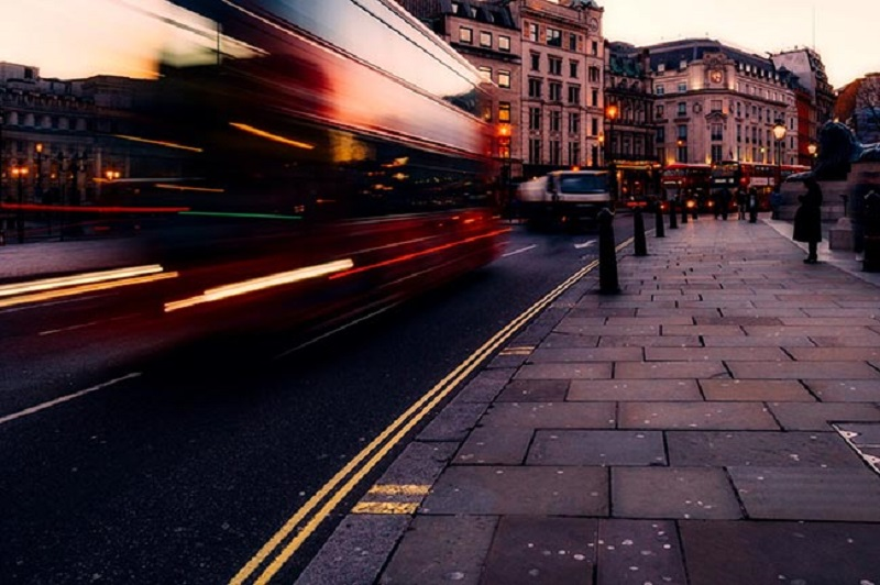 London street at dusk featuring truck and other vehicles plus a pavement