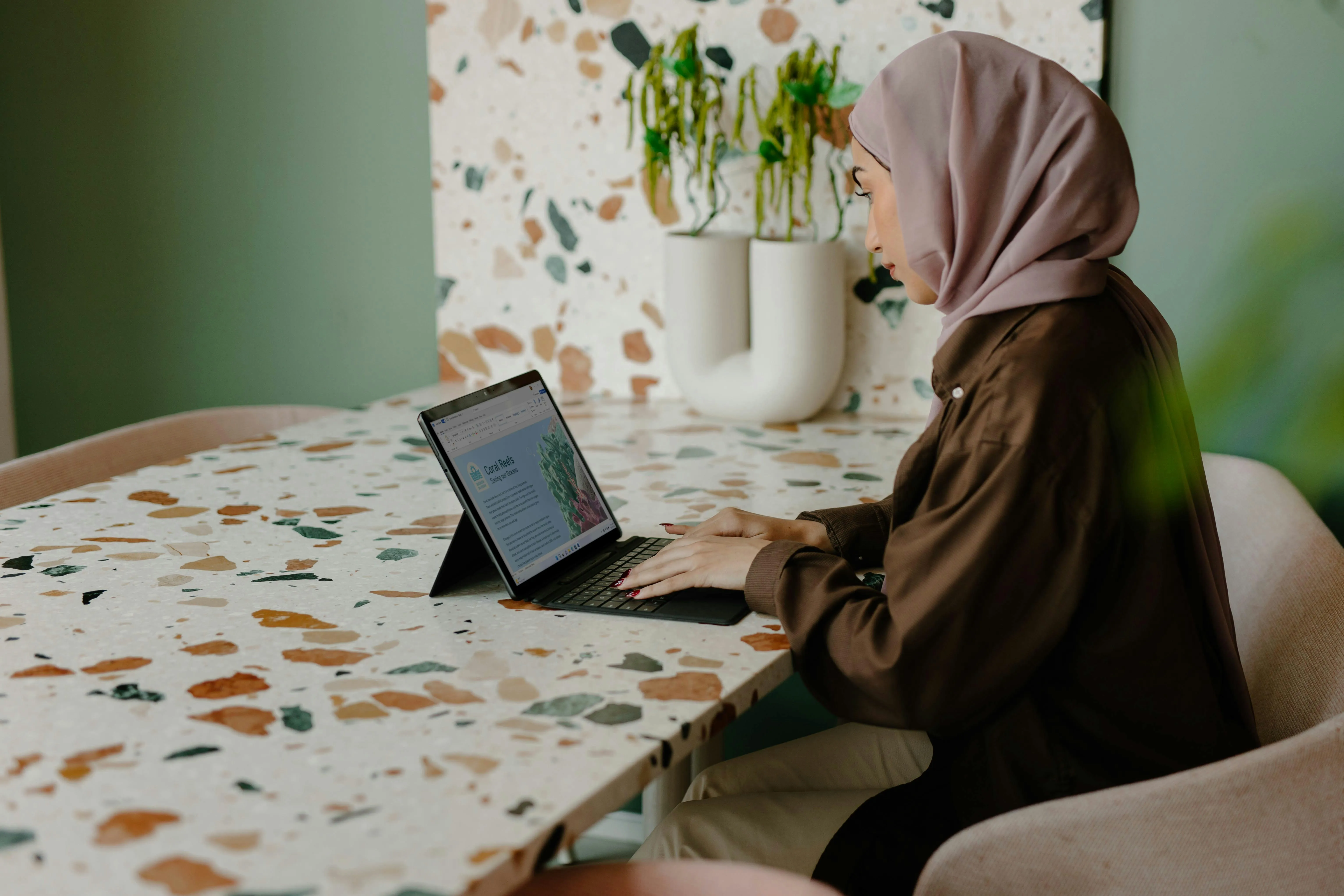 muslim lady with headscarf typing on ipad